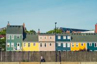 Image: person walking by row of homes. Topic: Green Home.