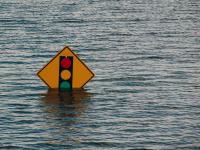 image of a traffic light sign mostly underwater thanks to flooding.