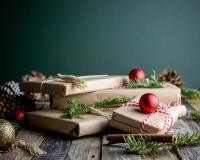 Gifts wrapped in brown paper with pine and ornaments around them. Sustainable gifts holidays.