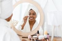 Black woman applying face products.