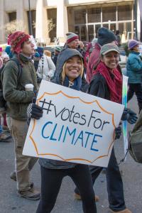 activist with sign that reads "hashtag Votes for Climate"