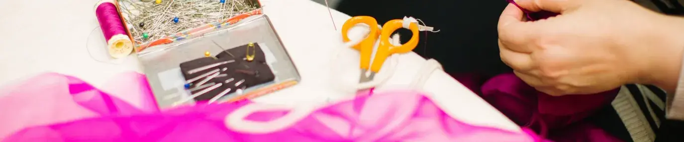 person holding pin using right hand and red mesh cloth using left hand