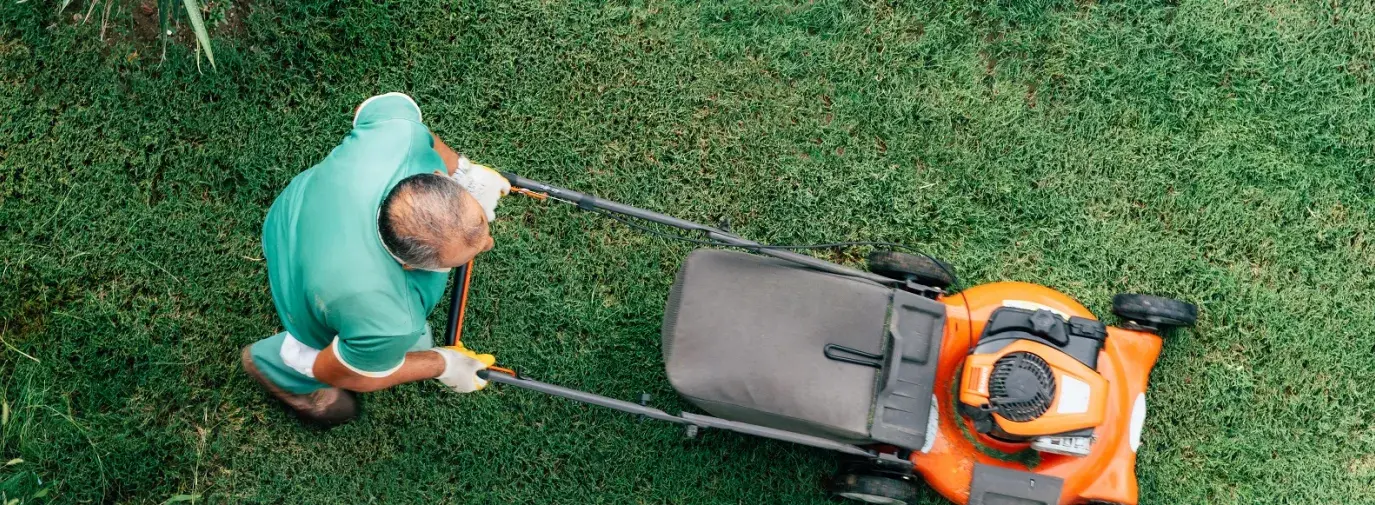 Image: man pushing an orange lawnmower. Article: 5 Steps To A More Eco-Friendly Lawn