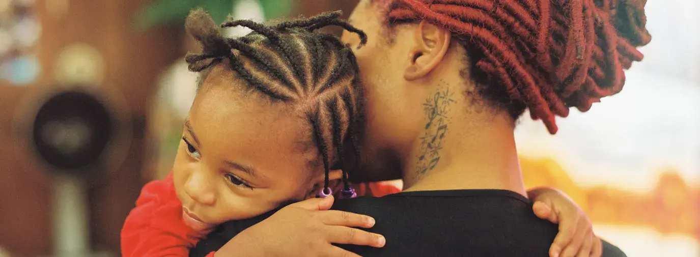 A Black mother and daughter embrace. Photo via Stocksy.