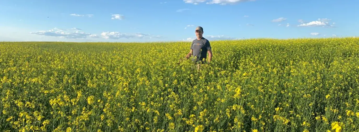 Tyler Streit smiling in a field of mustard flowers