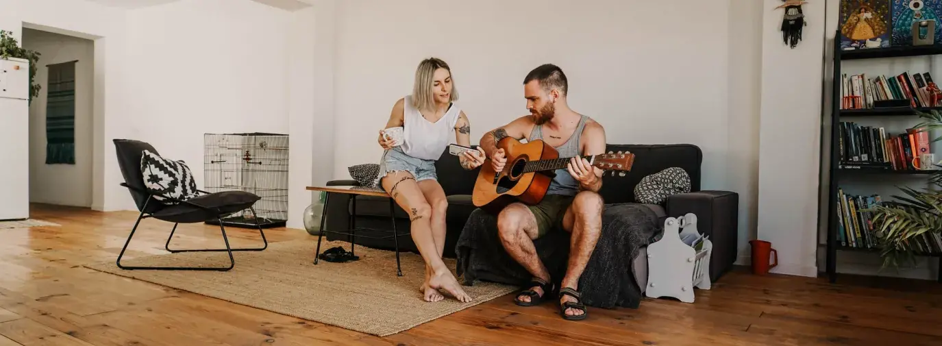 Image: man and woman in living room with wood flooring. Topic: Eco-friendly flooring